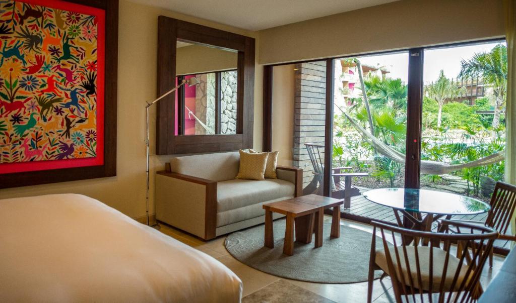 a bedroom with a bed and a couch and a table at Hotel Xcaret Arte - All Parks All Fun Inclusive - Adults Only in Playa del Carmen
