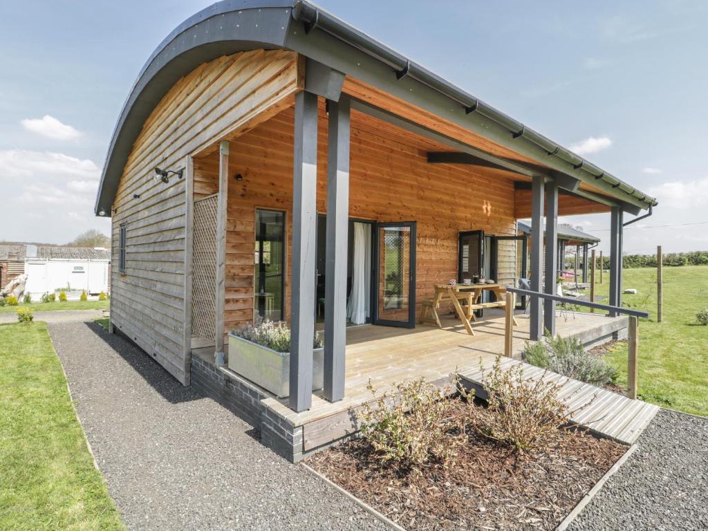 a wooden house with a large deck in a field at Primrose in Glastonbury