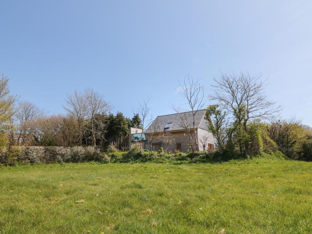 una casa en una colina con un campo de hierba en Northlands Country Cottage With Hot Tub, en Plymouth