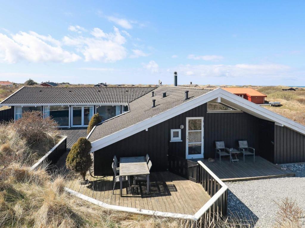 una casa negra con terraza y mesa en 12 person holiday home in Hj rring, en Lønstrup