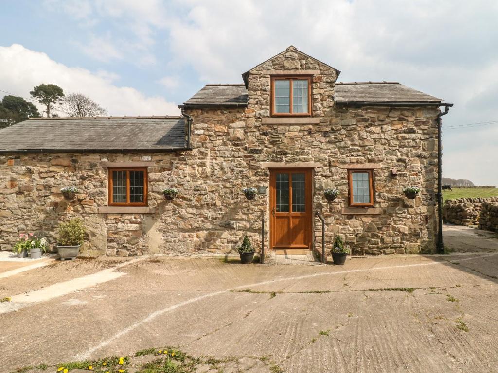 a stone house with a brown door and windows at Fletchers Barn in Alderwasley