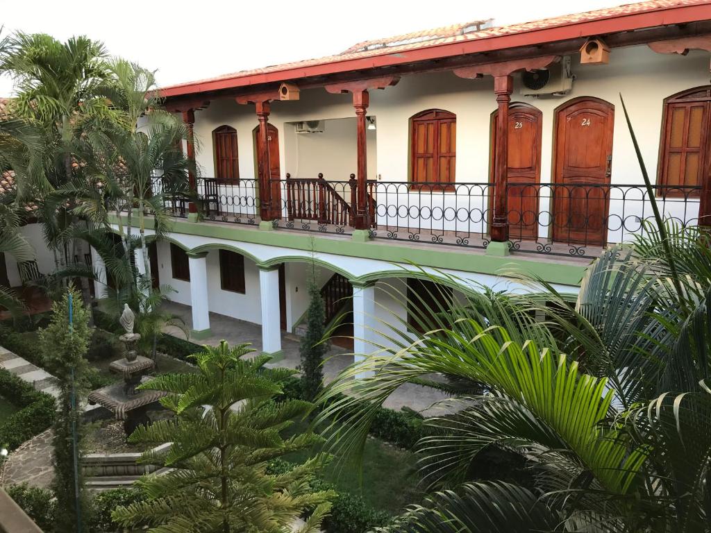 a building with a balcony and palm trees at Hotel Torogoz in Granada