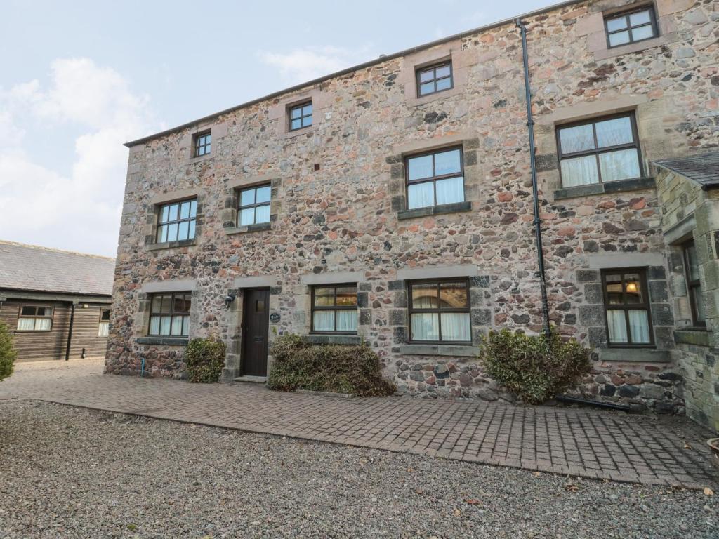 a large stone building with windows on it at Ivy Cottage in Wooler