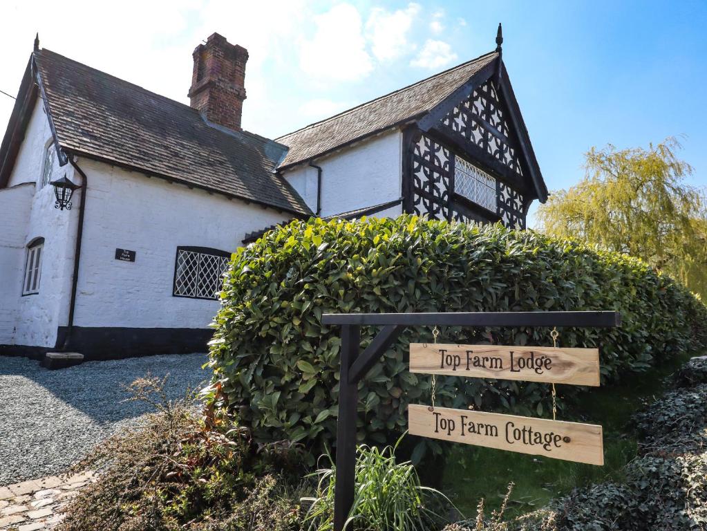 a house with a sign in front of a bush at Top Farm House in Oswestry