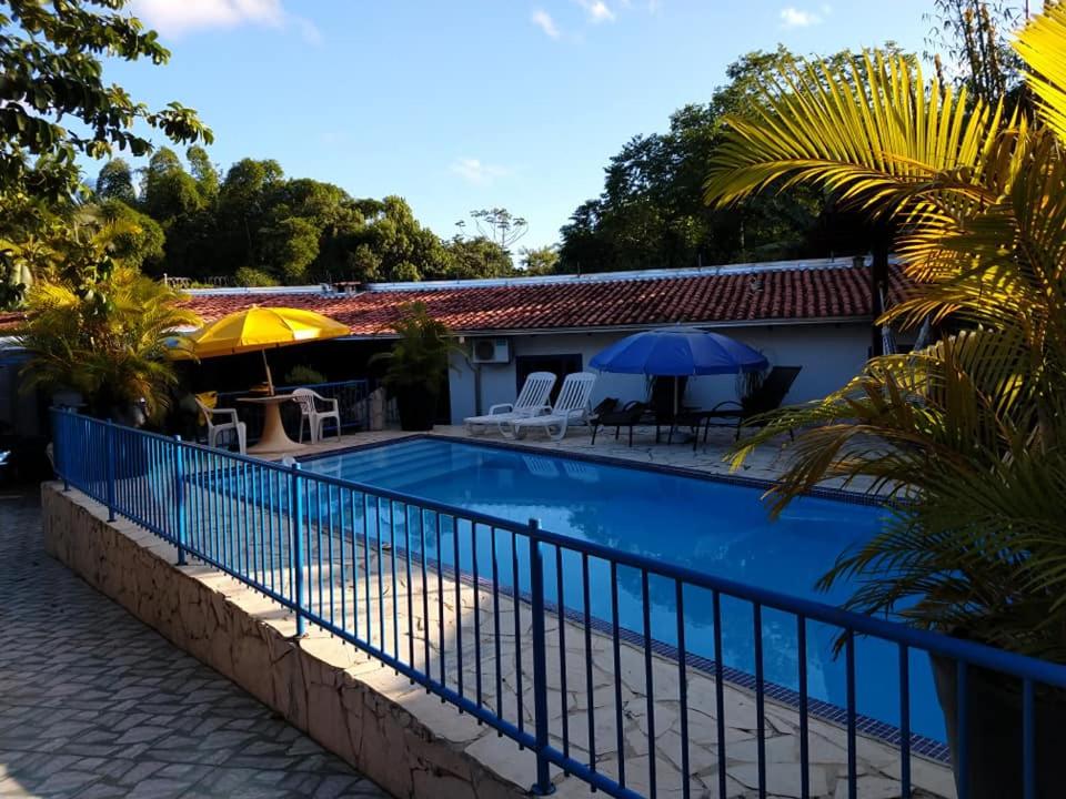 a swimming pool with a blue fence next to a house at Rancho Velho Tropeiro in São Francisco do Sul