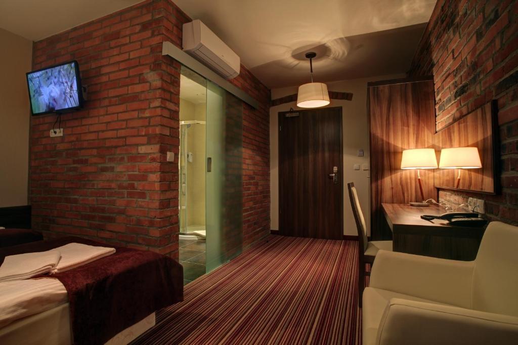 a hotel room with a bed and a brick wall at Browar CzenstochoviA Hotel&Spa in Częstochowa