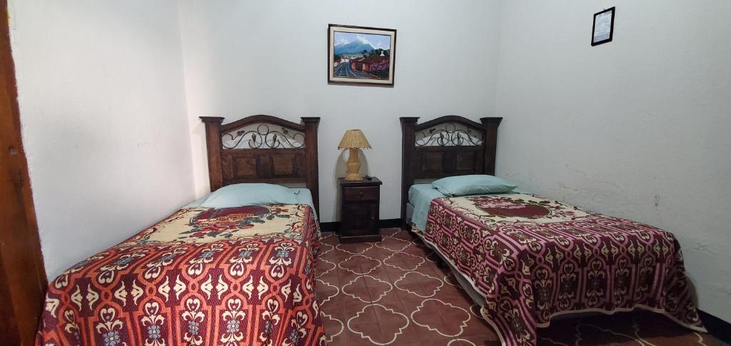 Habitación con 2 camas y lámpara. en Hotel Posada Santa Teresita, en Antigua Guatemala