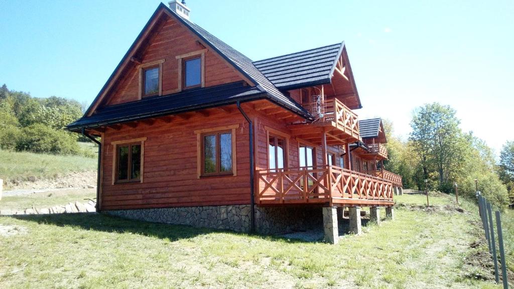 ein großes Holzhaus mit Balkon auf einem Feld in der Unterkunft Słoneczne Chaty Kasina Wielka in Kasina Wielka