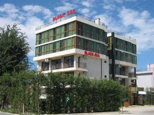 a tall building with a red sign on top of it at Family Hotel Black Sea in Sunny Beach