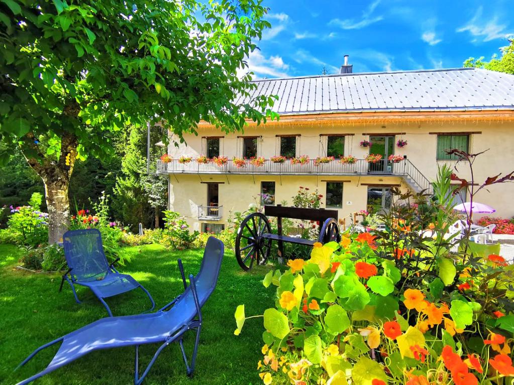 dwa niebieskie krzesła na podwórku domu w obiekcie Le Moulin des Olirics w mieście Sallanches