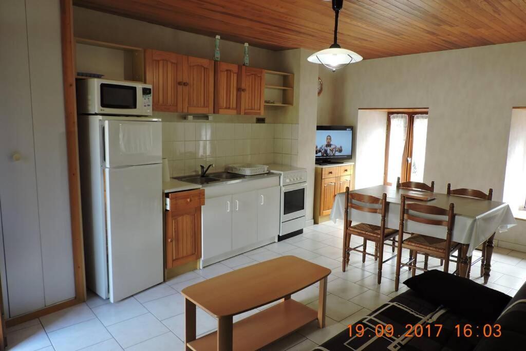 a kitchen with a table and a white refrigerator at Gite au pied du mont Lozère 2 in Mas-dʼOrcières