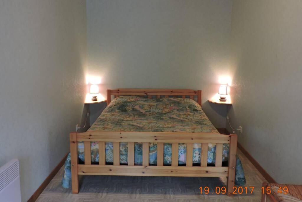 a bedroom with a wooden bed with two lights on it at Gite au pied du mont Lozère 2 in Mas-dʼOrcières