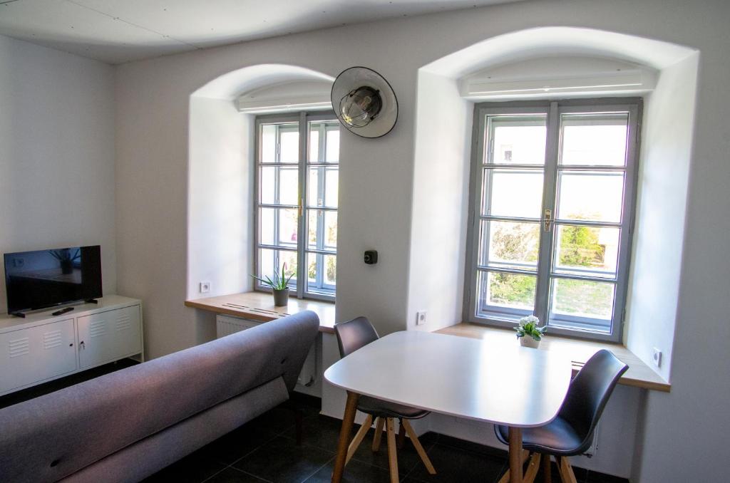 a living room with a couch and a table and two windows at Garsoniéra Sedlecká v centru Kutné Hory in Kutná Hora