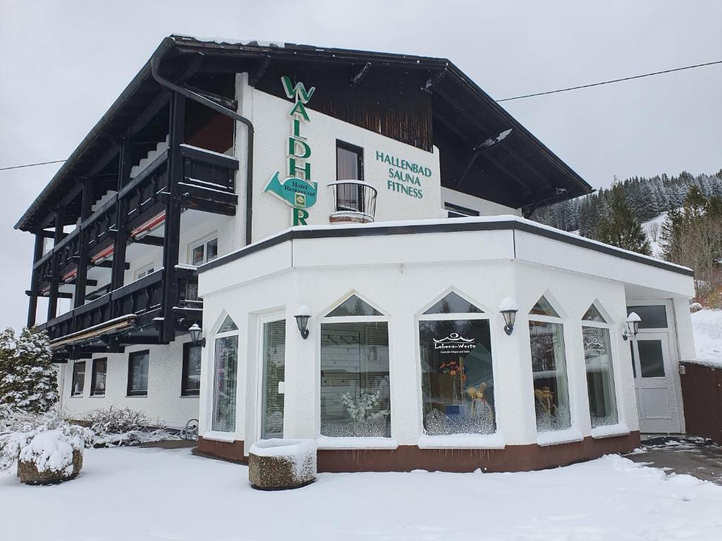 a white building with a sign on it in the snow at HOTEL WALDHORN in Jungholz