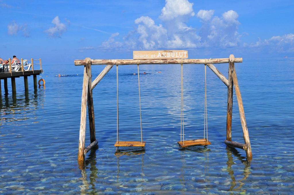 a wooden bridge in the water with swings at Hotel Akbulut & Spa in Güzelçamlı