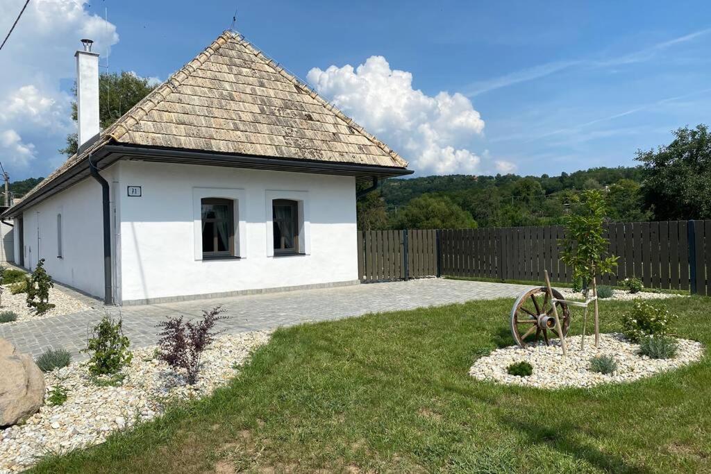un pequeño edificio blanco en un patio con una valla en Biely domček so záhradou v malej obci Devičie, en Devičie