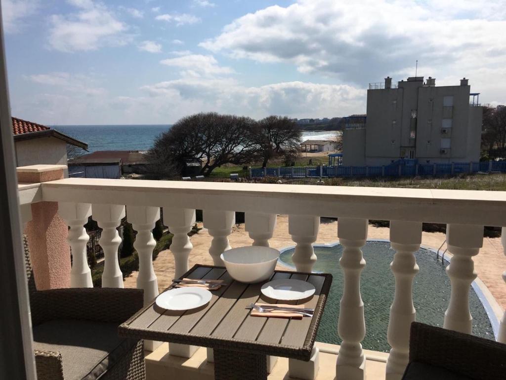 a table on a balcony with a view of the ocean at Студио Симона 2 - първа линия море in Lozenets
