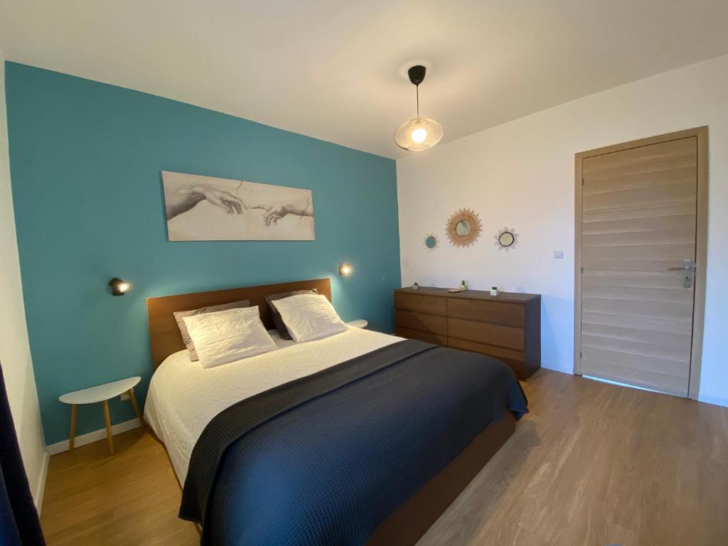 ein Schlafzimmer mit einem großen Bett und einer blauen Wand in der Unterkunft Le 44 - T2 rénové moderne et confortable en centre-ville in Montluçon