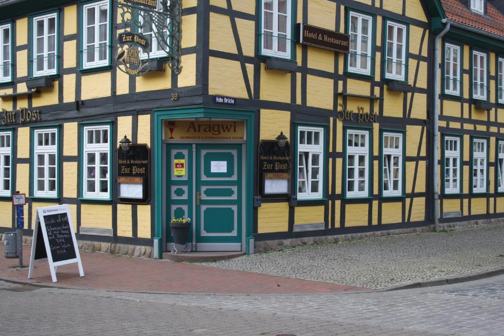 ein gelbes und schwarzes Gebäude mit einem Schild davor in der Unterkunft Hotel & Restaurant Aragwi in Salzwedel