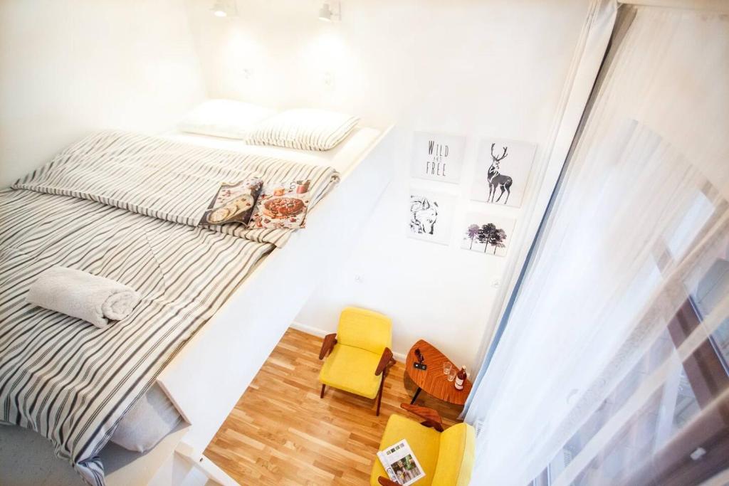 um pequeno quarto com uma cama e uma cadeira amarela em The Tiny Space 6m2 with private bathroom in the hallway em Sopot