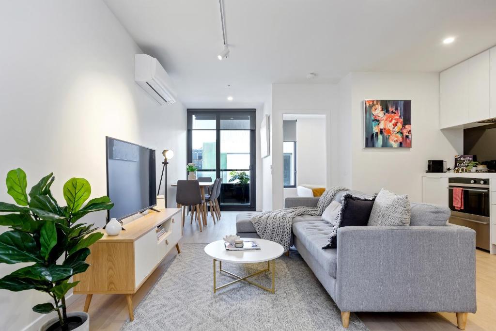 a living room with a couch and a tv at Palmerston St Apartments by Urban Rest in Melbourne