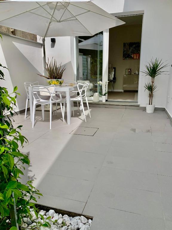 a patio with a table and chairs and an umbrella at Villa Luminosa in Torre del Lago Puccini