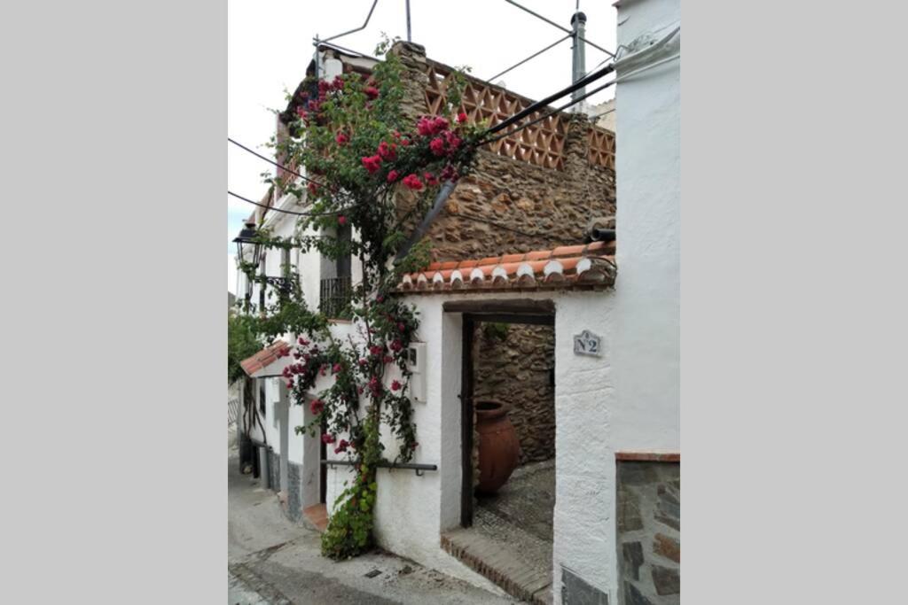ein weißes Gebäude mit Blumen auf der Seite in der Unterkunft Casa Fuensanta balcón al mar de la Alpujarra in Granada