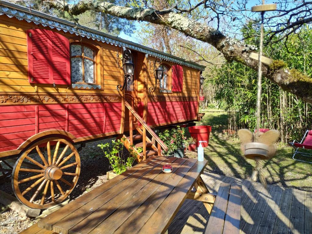 une petite maison avec un wagon en bois dans une cour dans l'établissement Les roulottes Vesta, à Léognan