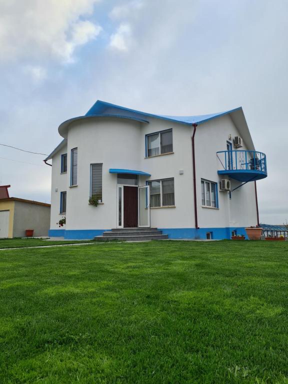 Casa blanca con techo azul y césped en Casa Matei, en Mahmudia