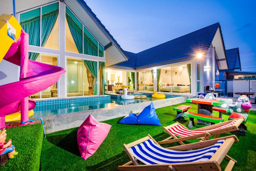 una casa con un patio con sillas y una piscina en M4 Billion Pool Villa Cha-am en Cha Am