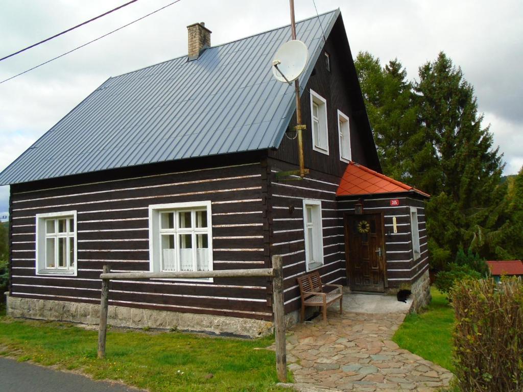 ein kleines schwarzes Haus mit einer Holztür in der Unterkunft Chata Pilka in Nové Hamry