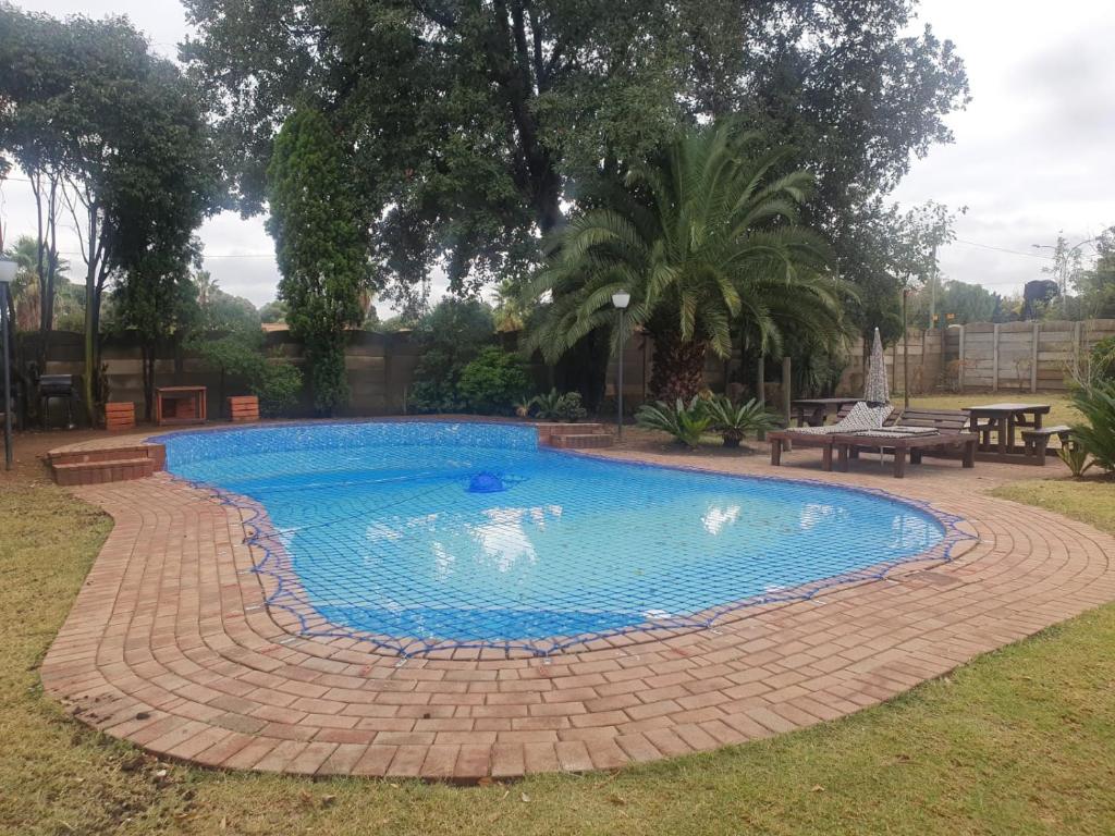 una piscina en un patio con una pasarela de ladrillo alrededor en SM Africa Guest House, en Alberton
