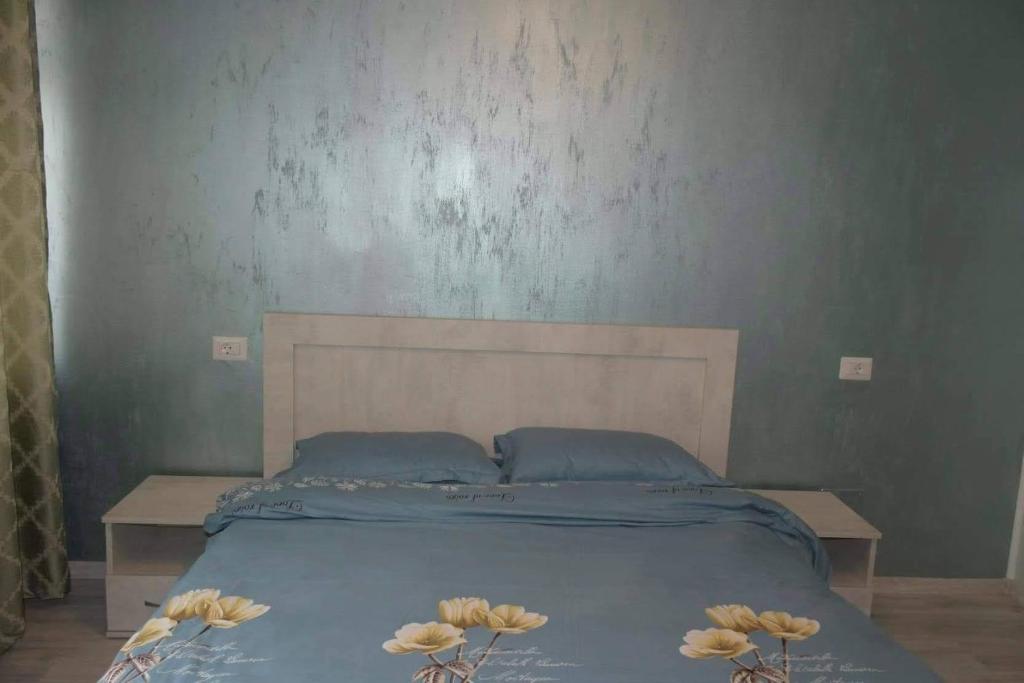 - un lit avec des draps bleus et trois fleurs dans l'établissement Pensiunea Red Rock, à Piatra Neamţ