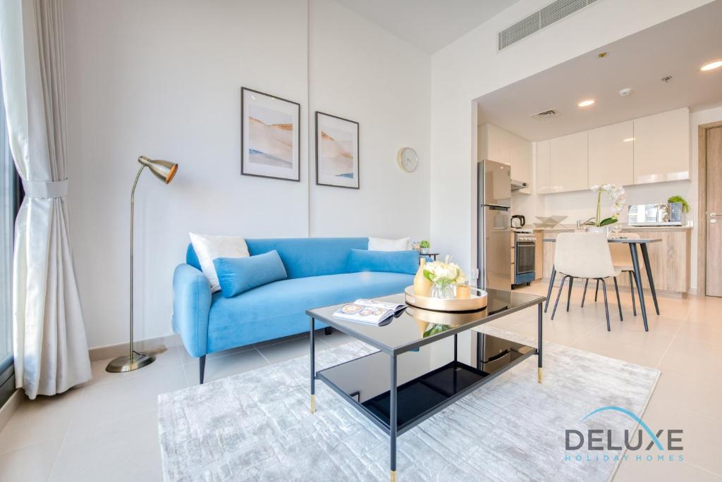 a living room with a blue couch and a table at Chic 1BR in Town Square UNA Dubailand by Deluxe Holiday Homes in Dubai