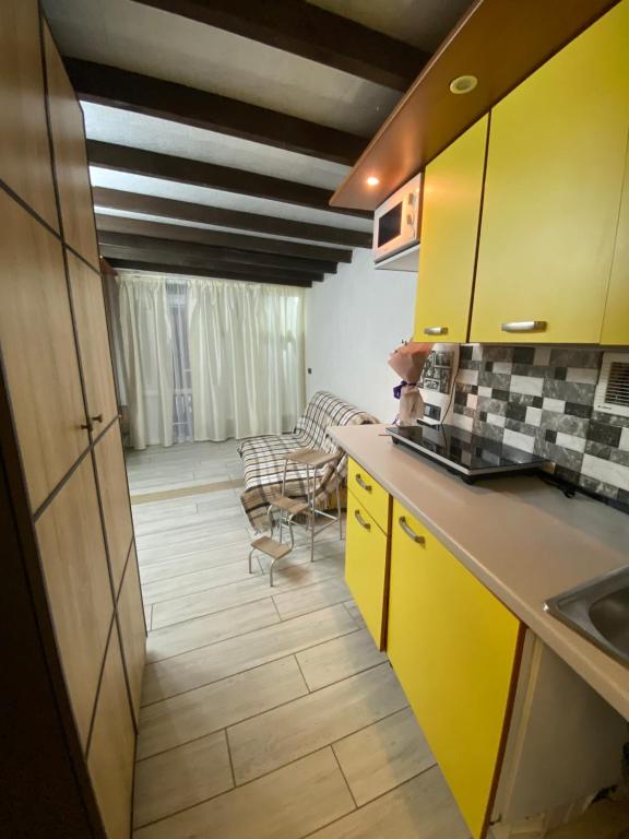 House&House 84 في Petropavlovskaya Borshchagovka: مطبخ مع دواليب صفراء وغرفة معيشة