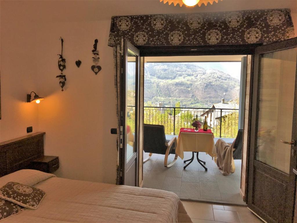 a bedroom with a door open to a balcony with a table at Affittacamere Verger Plein Soleil in Saint-Pierre