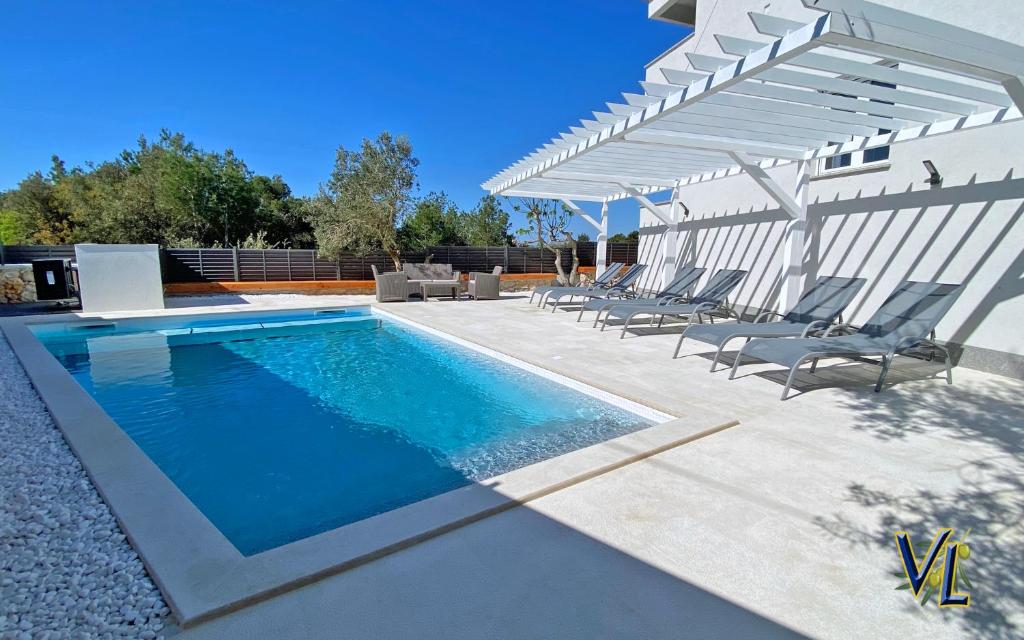 a swimming pool with chairs and a pergola at Apartment PASMAN - appartement 50 m2 et piscine in Pakoštane