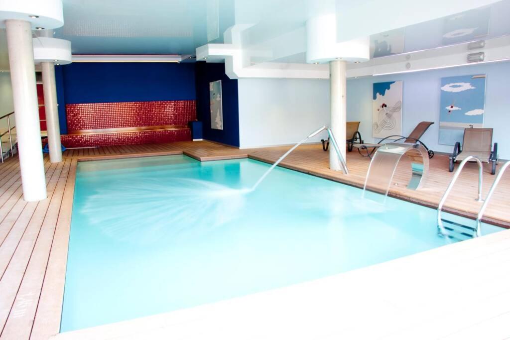 einen Pool mit Stühlen in einem Zimmer mit blauen Wänden in der Unterkunft CHALET CERCA DE NOJA CON ACCESO A SPA in Beranga