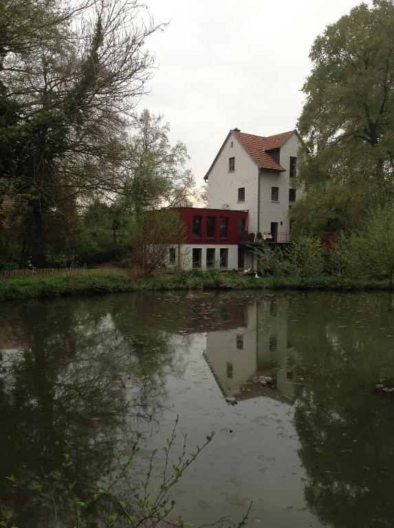 une maison assise à côté d'une nappe d'eau dans l'établissement Wassermühle, à Rheine