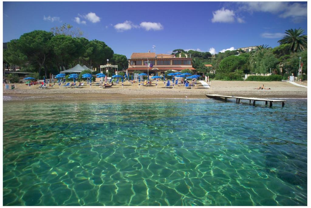 a large pool of water with a beach with umbrellas at Frank's Hotel in Capoliveri