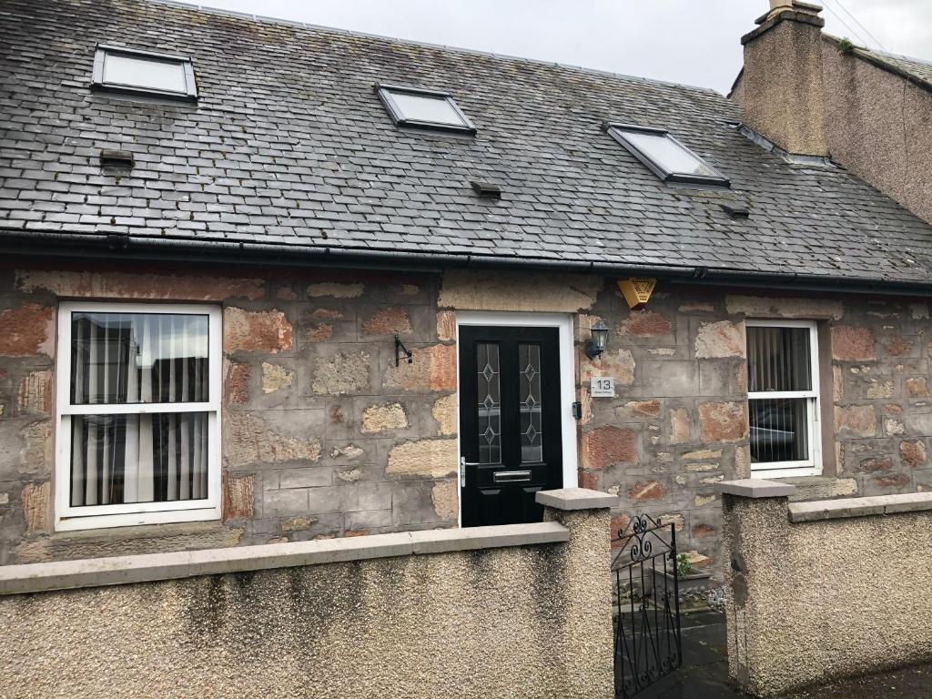 an old stone house with a black door and windows at Rose Cottage in Inverness
