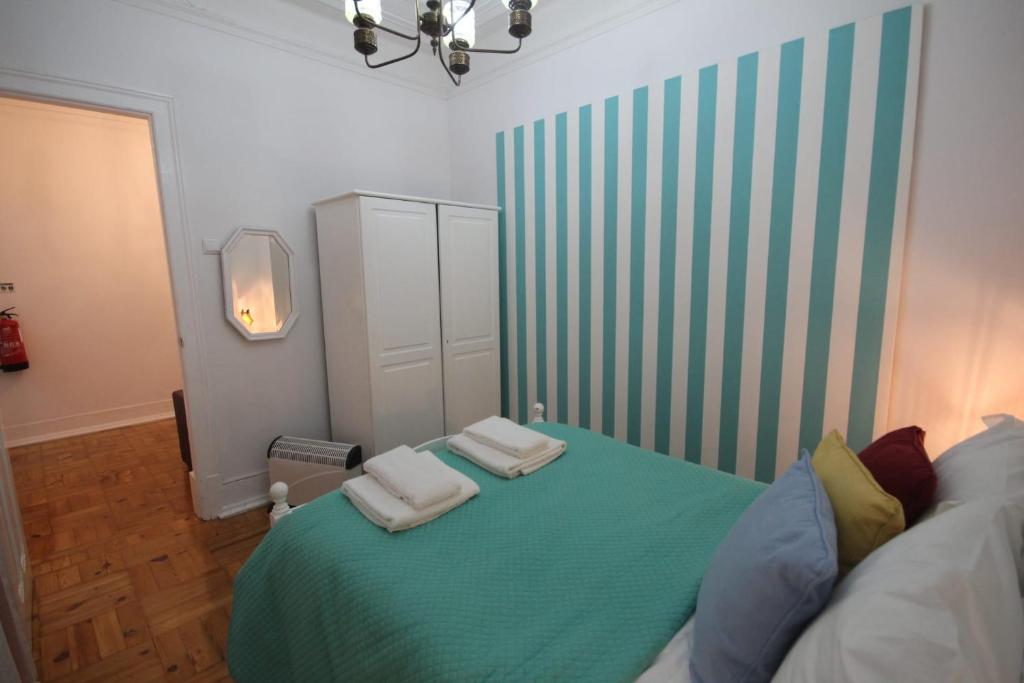 リスボンにあるClassy and cozy Double room in Marques de Pombal, Nautic, with shared Bathroomのベッドルーム1室(緑のベッド1台、タオル2枚付)