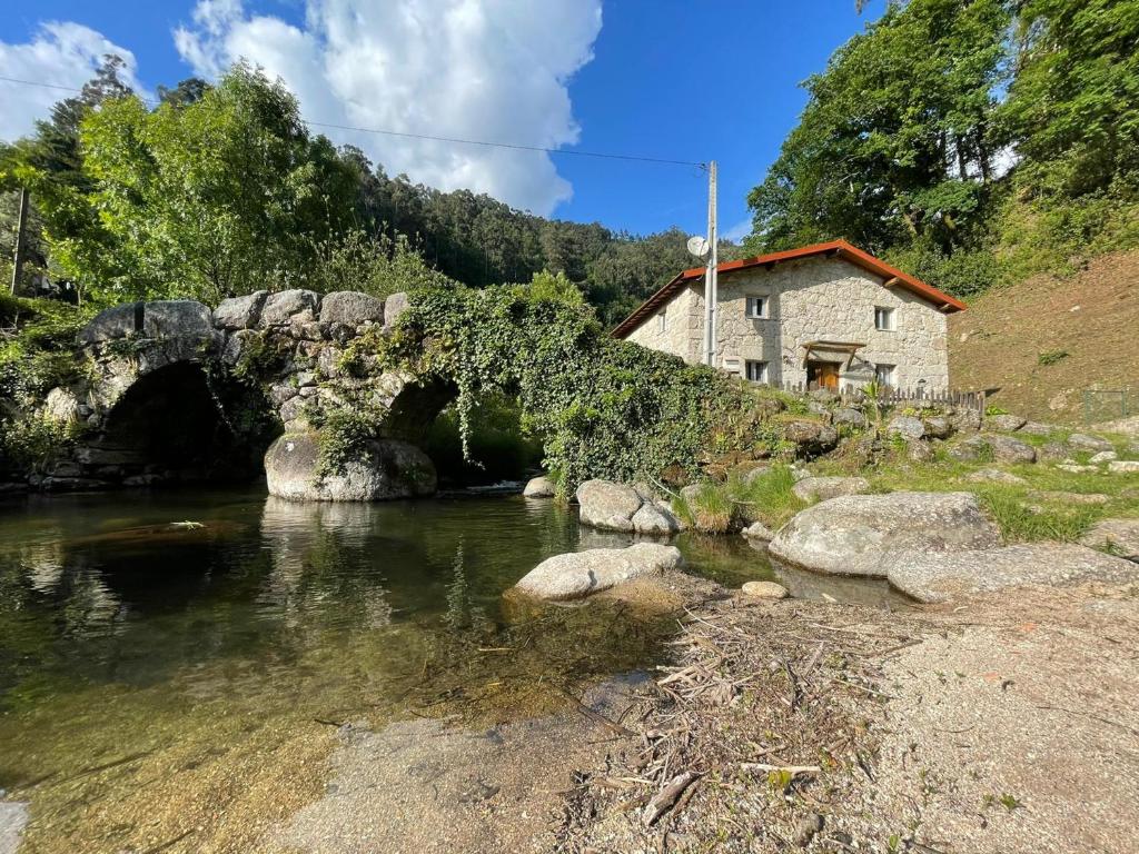 eine Brücke über einen Fluss neben einem Gebäude in der Unterkunft Casa Museu Lagar de Azeite in Terras de Bouro
