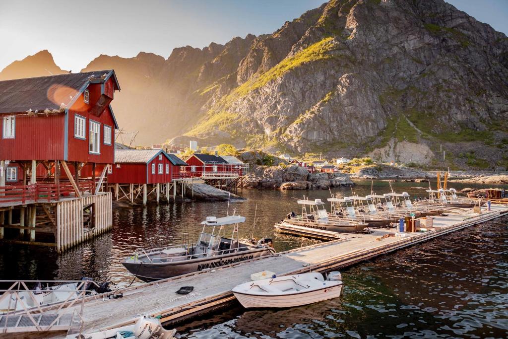 un groupe de bateaux amarrés à un quai avec une montagne dans l'établissement Å Rorbuer - by Classic Norway Hotels, à Å