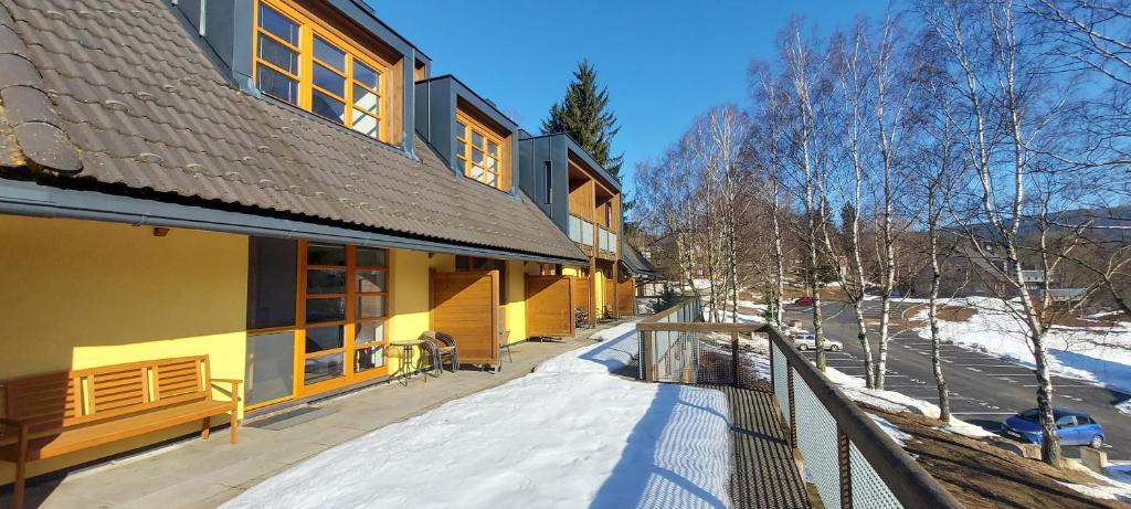 ein Gebäude mit einem schneebedeckten Gehweg neben einem Gebäude in der Unterkunft Wellness apartmány Říčky in Říčky