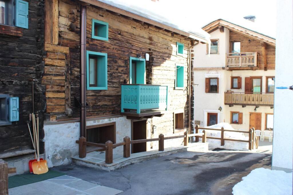 un edificio de madera con un balcón azul. en Snowflake Apartment - Livigno, en Livigno