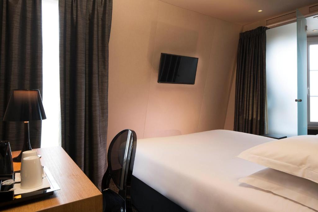 a hotel room with a bed and a table with a lamp at Best Western Quartier Latin Pantheon in Paris