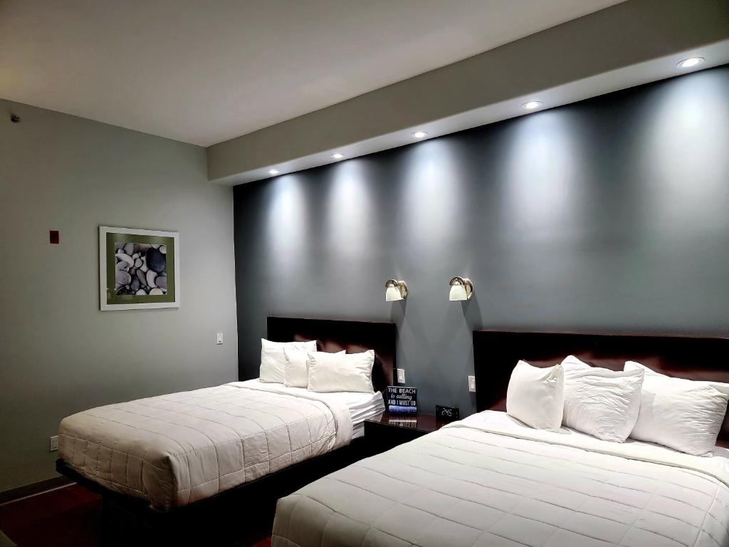 Cette chambre d'hôtel comprend 2 lits avec des draps blancs. dans l'établissement Blue Bay Inn and Suites, à South Padre Island