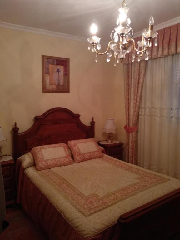 een slaapkamer met een bed met een kroonluchter bij Casa Freitas in Combarro