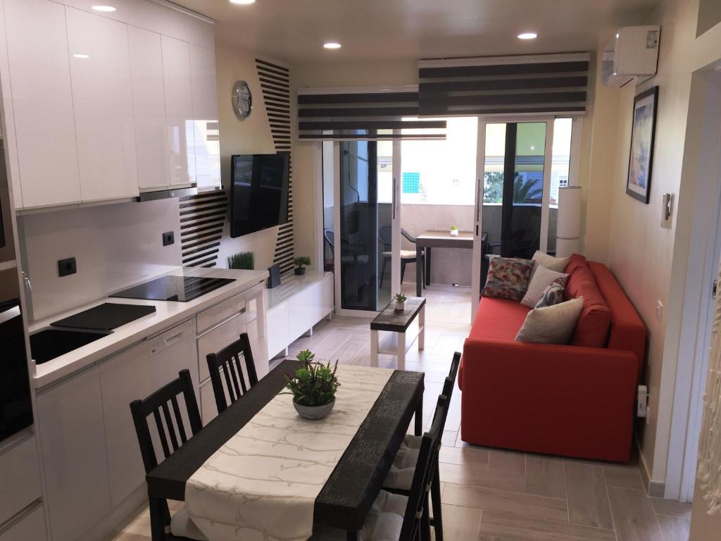 a kitchen and living room with a table and a red couch at Atlantic Coast Apartment - Playa Del Inglés in Playa del Ingles